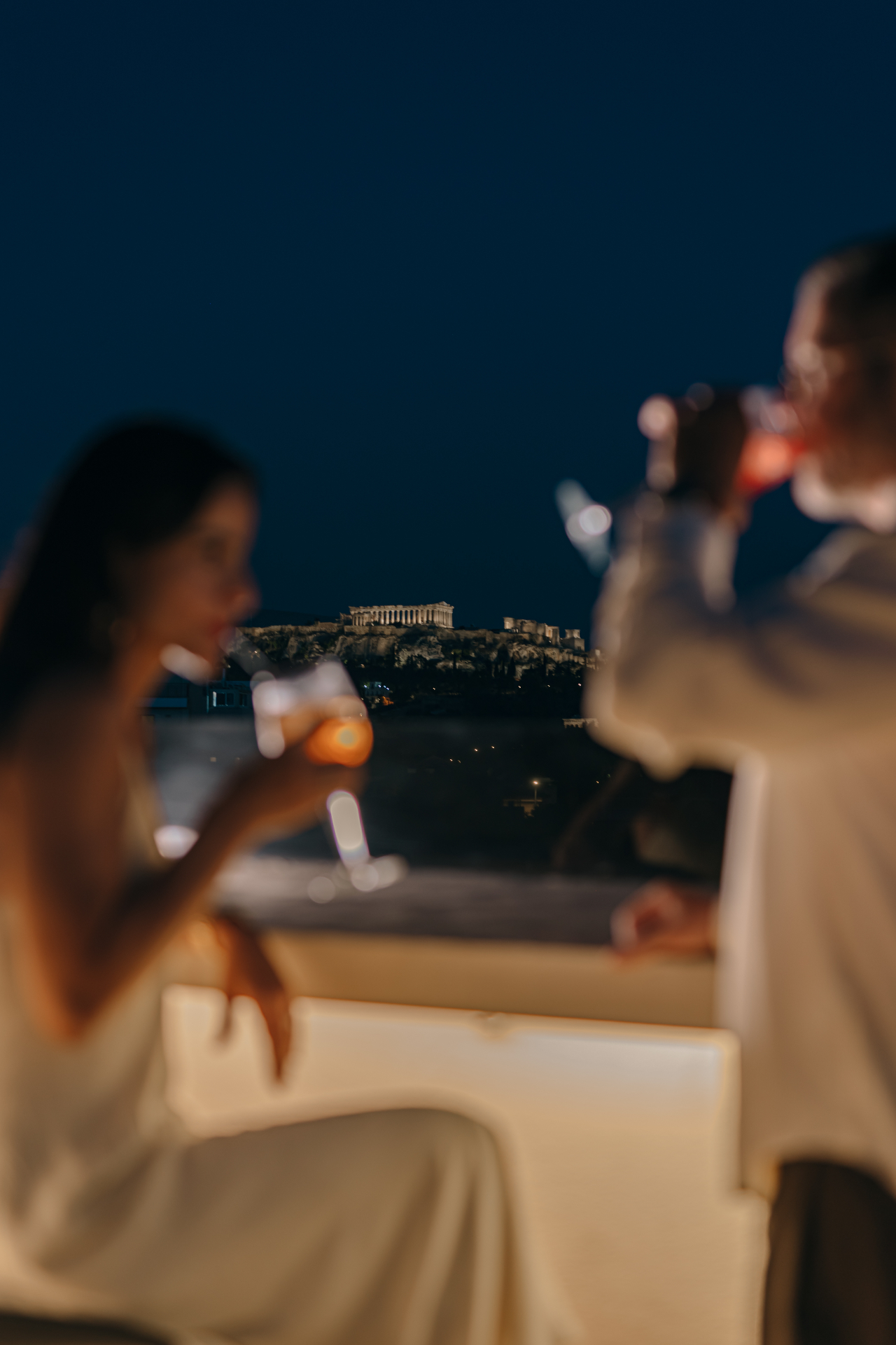 Two spritz cocktails with the illuminated Parthenon behind