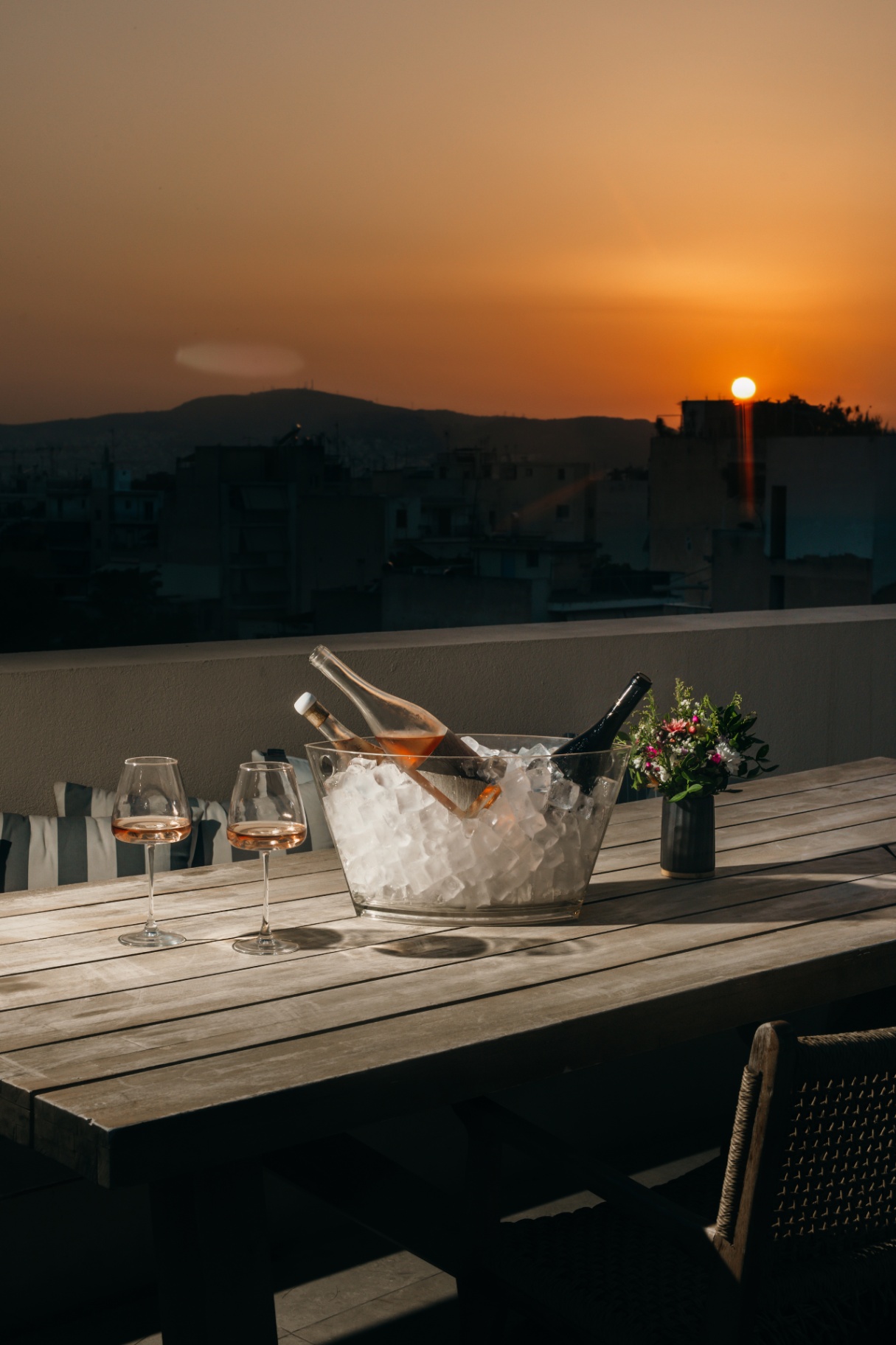 Wine chilling in a bucket on a wooden rooftop table at sunset
